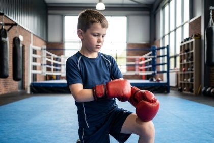 Jeune garçon de boxe prêt à s'entraîner dans un gymnase moderne