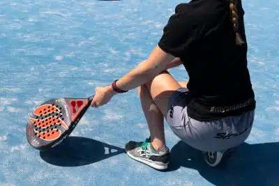 a woman sitting on a tennis court holding a racquet