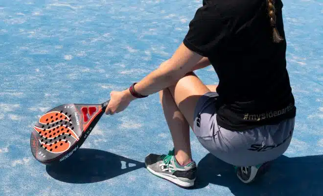 a woman sitting on a tennis court holding a racquet