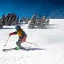 person in red jacket and blue pants riding on ski blades on snow covered ground during